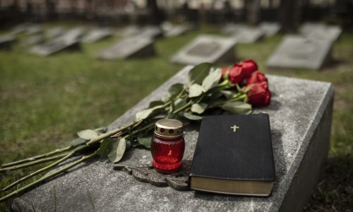 Lápide com bíblia e flores indicando a vida após a morte.
